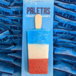 Paleta Factory’s red, white, and blue paleta, featuring strawberry, lime, and blue raspberry flavors, in individually wrapped signature blue packaging.